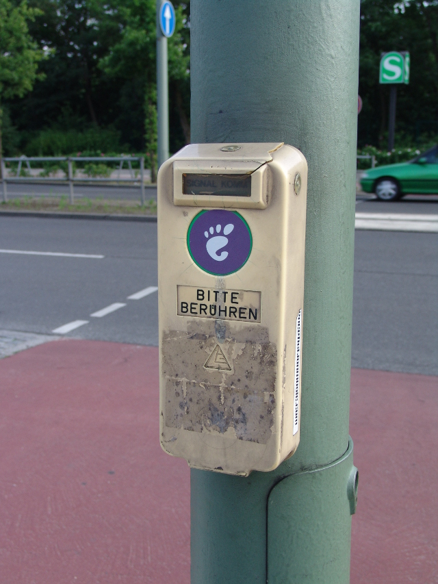 Gnome sticker on a crosswalk button, above it says in German "please
touch"